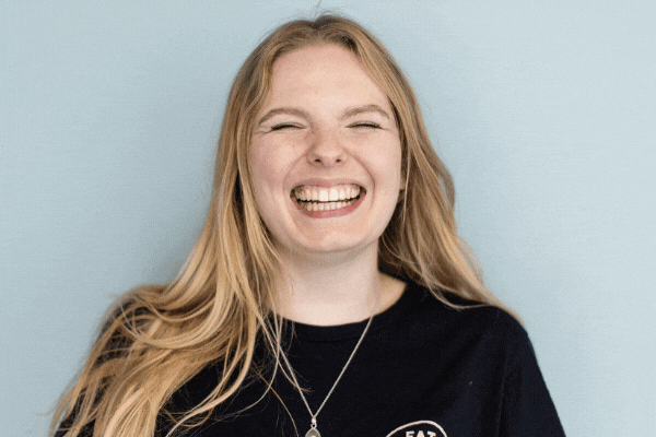 GIF of TeamStemette Lucy smiling and posing against a light wall