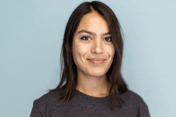 GIF of TeamStemette Julia smiling and posing against a light wall