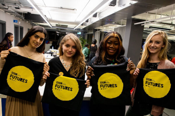 Four people at a Stemettes event holding up Stemette Futures bags.