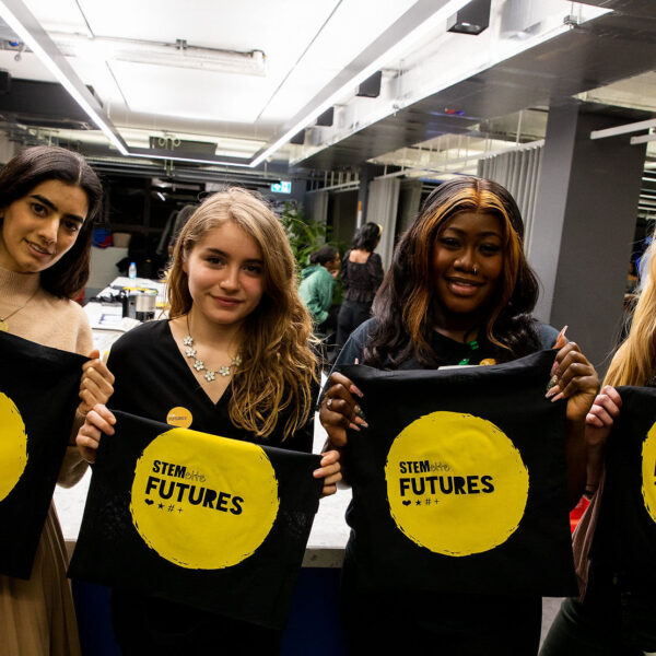 Four people at a Stemettes event holding up Stemette Futures bags.
