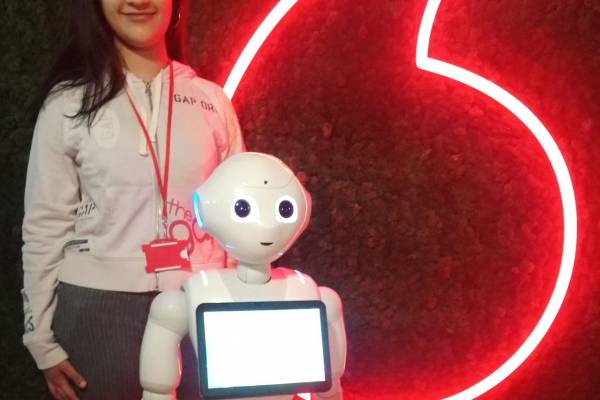 Nisa Anwer in front of a Vodafone logo with a chatbot.