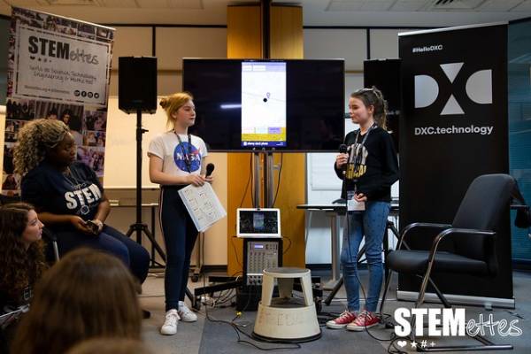 Two Stemettes presenting in front of a DXC Technology and Stemettes banner.