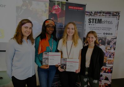 Four Stemettes posing at a BAE Systems event, two are holding certificates.
