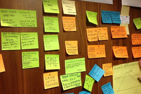A wall full of post it notes with writing on them.
