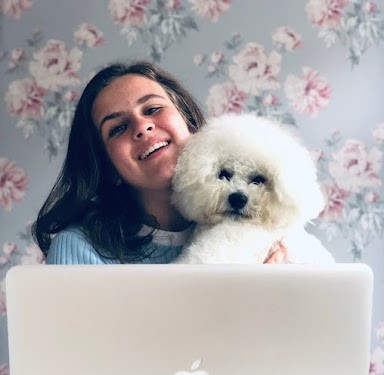Lella Violet Halloum and her dog in front of a floral wall with a macbook.