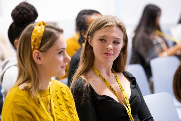Two Stemettes sitting in an audience talking to eachother.