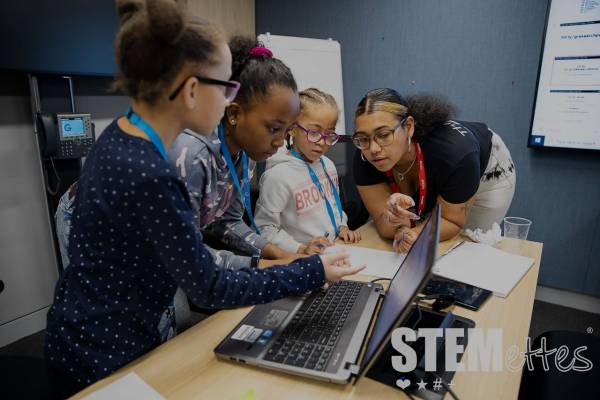 Team Stemette Jazmin helping young Stemettes on a computer.