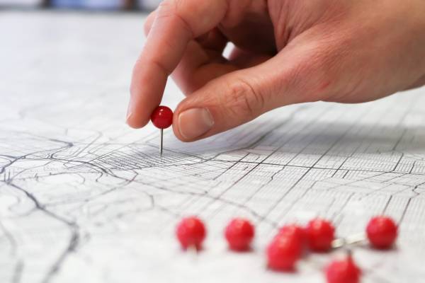 hand adding a pin point to a map
