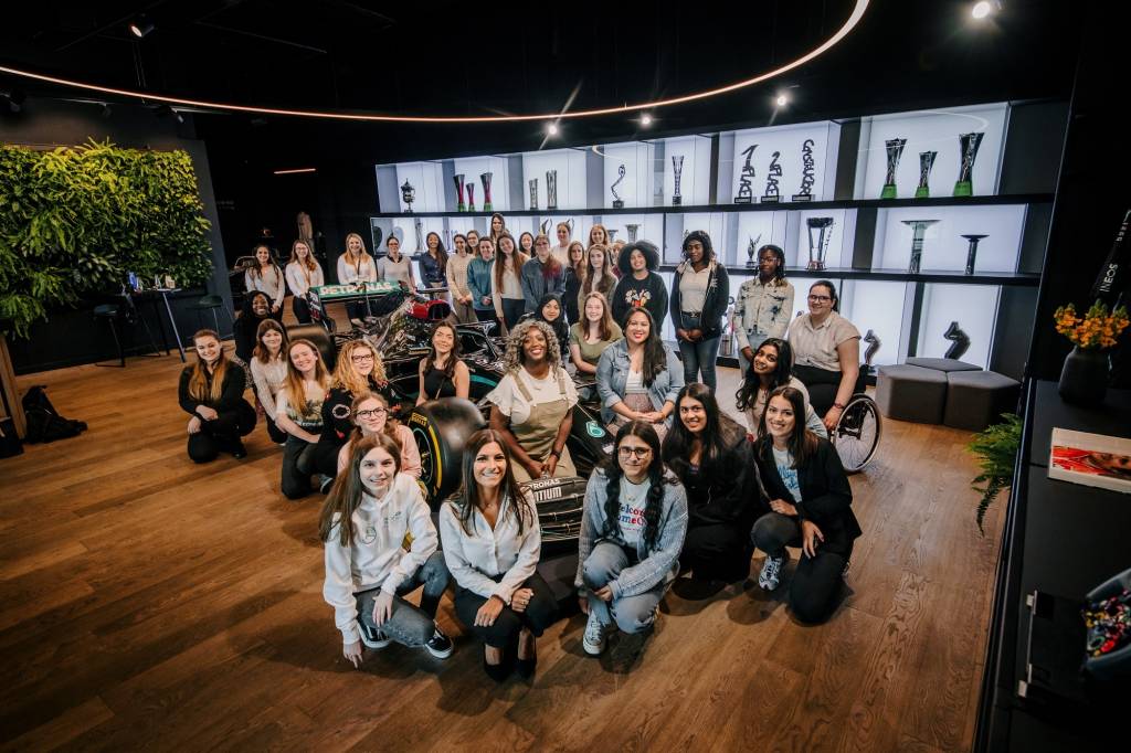 Stemettes group sat around a MBGP F1 car, in front of trophy cabinet