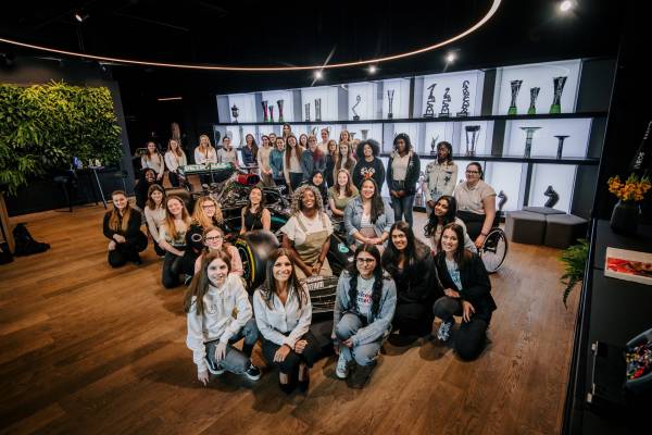 Stemettes group sat around a MBGP F1 car, in front of trophy cabinet.