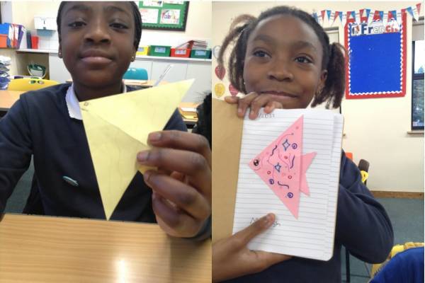 2 images side by side showing two school children holding up their origami fish creations.