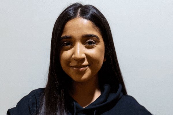 GIF of TeamStemette Nailah smiling and posing against a light wall
