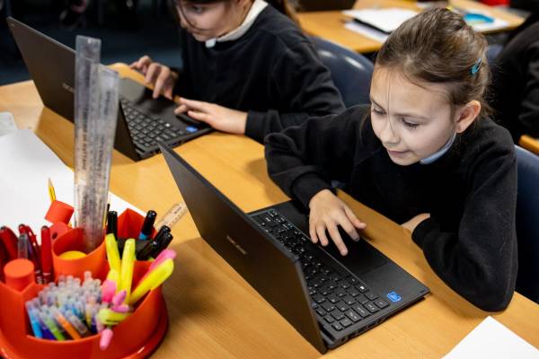 Two School Stemettes sit and work on laptops.