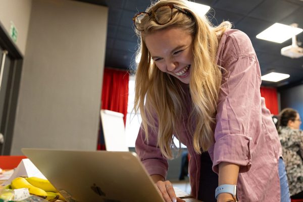 A member of Team Stemette stands and smiles at their laptop.