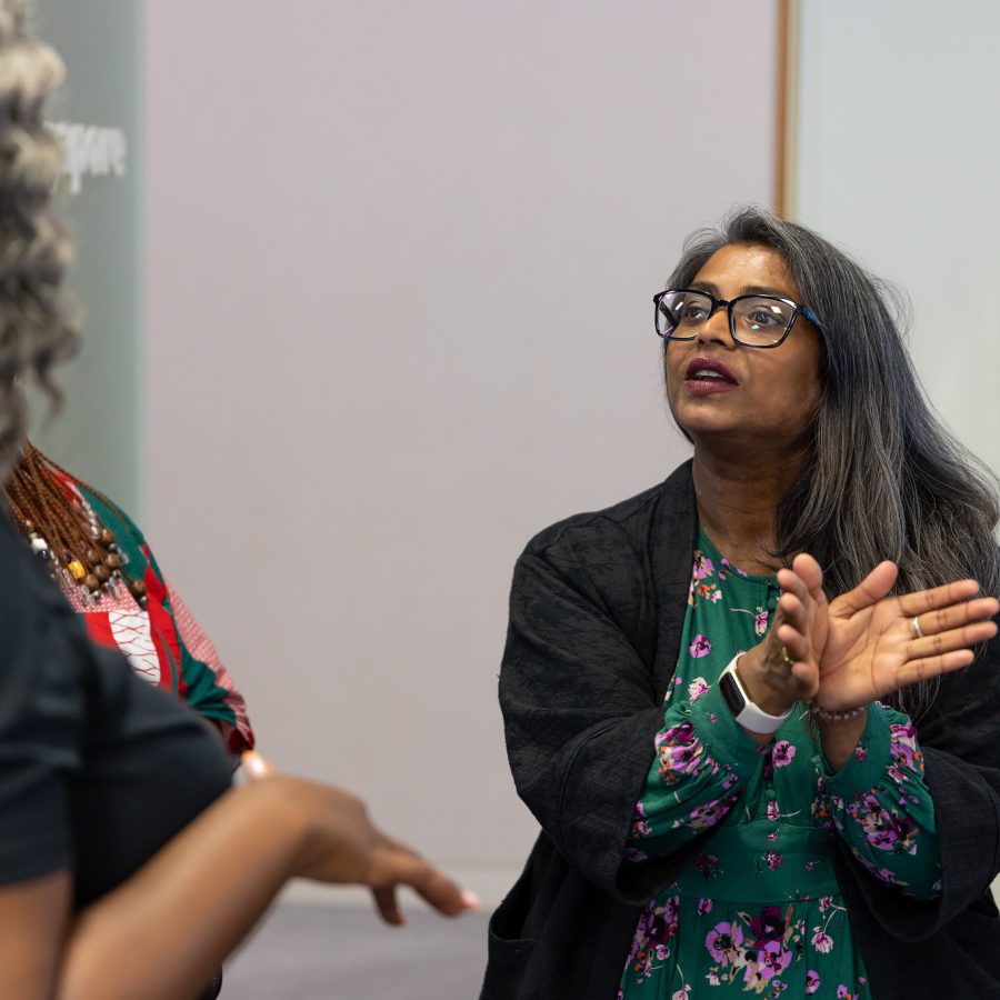 A person stands and talks to Head Stemette Anne-Marie, using their hands to describe what they are saying.