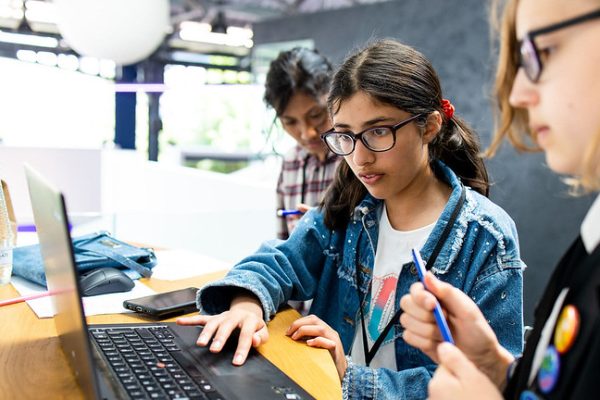 Three Stemettes work together around a laptop.