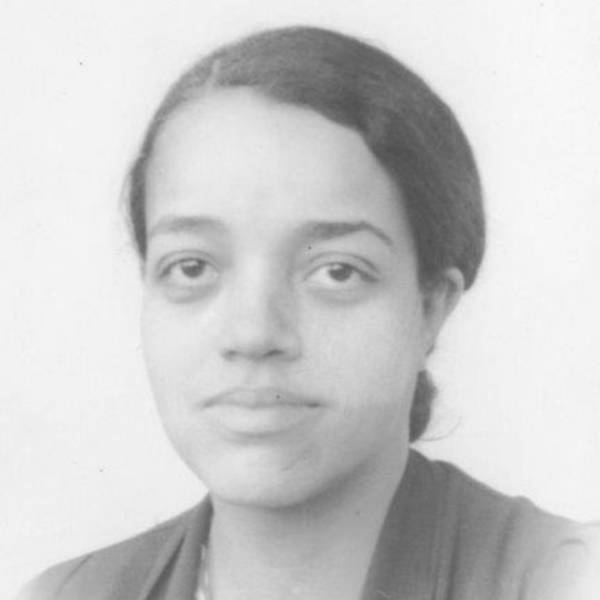 Dorothy Vaughan is smiling at the camera. She has long hair in a low bun and is wearing a smart jacket. The image is in black and white.
