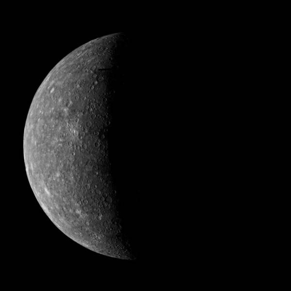 Mercury with a shadow across half of it. Craters are visible.